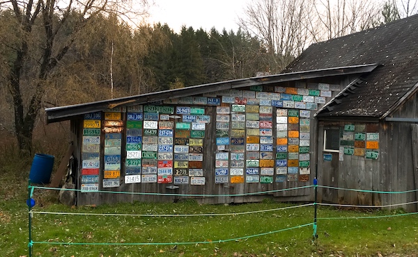 side of a barn entirely covered with license plates