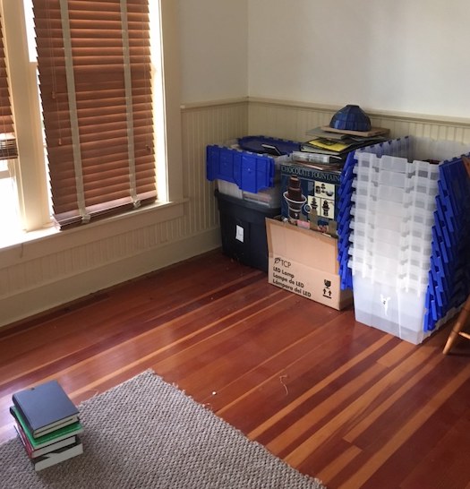 a few plastic tubs on a floor that looks like it used to have more of them. A small pile of books.