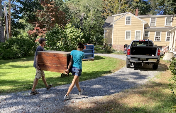 two people walking outside with a big cedar chest